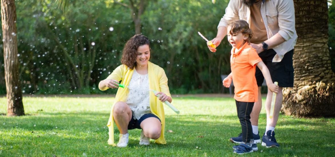 A family enjoys a playful day with bubbles in a sunny park setting.