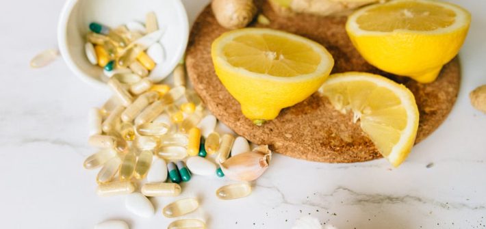 Sliced lemons and various supplements on a corkboard, symbolizing natural health remedies.